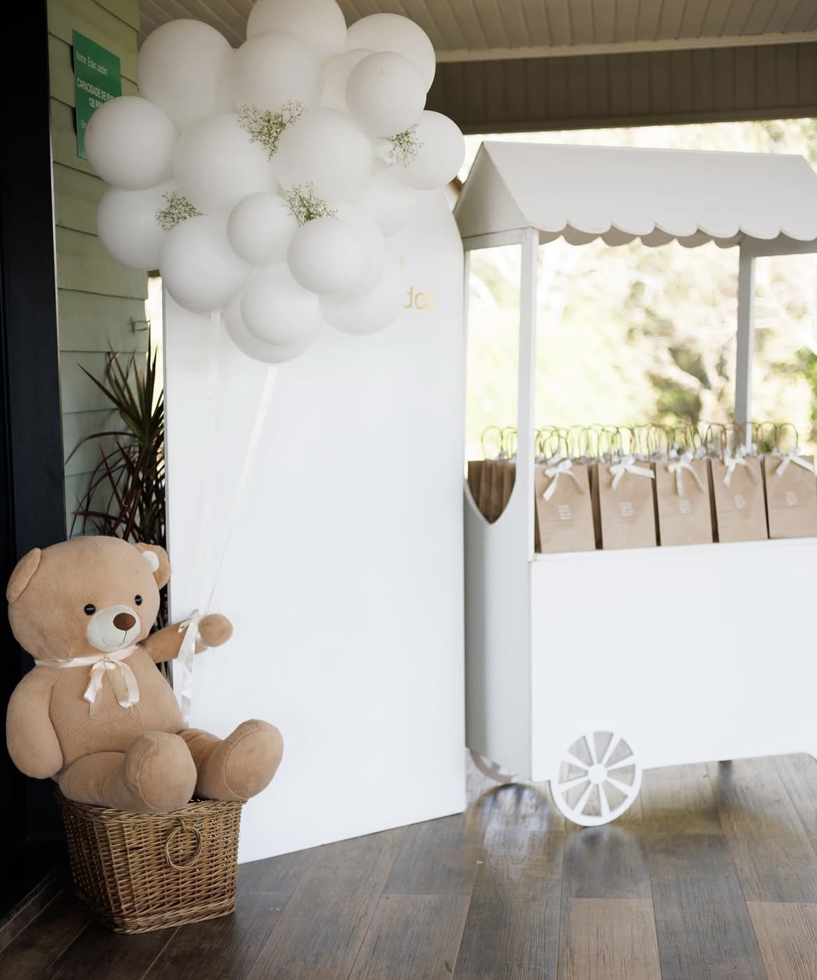 Urso de pelúcia com balões e carrinho de lembrancinhas